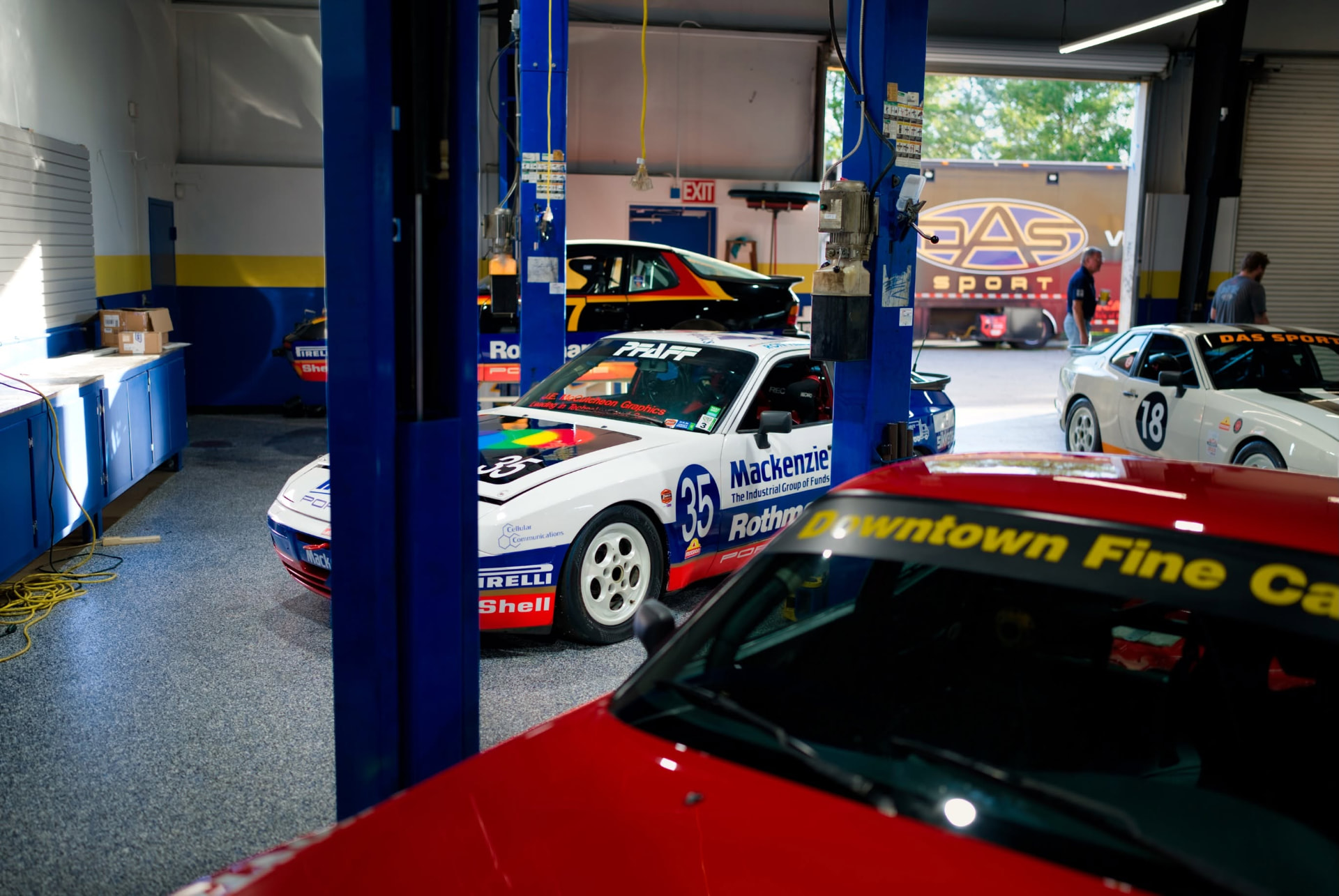 Vintage Porsche 944 race cars on lifts inside the DAS Sport workshop in Savannah