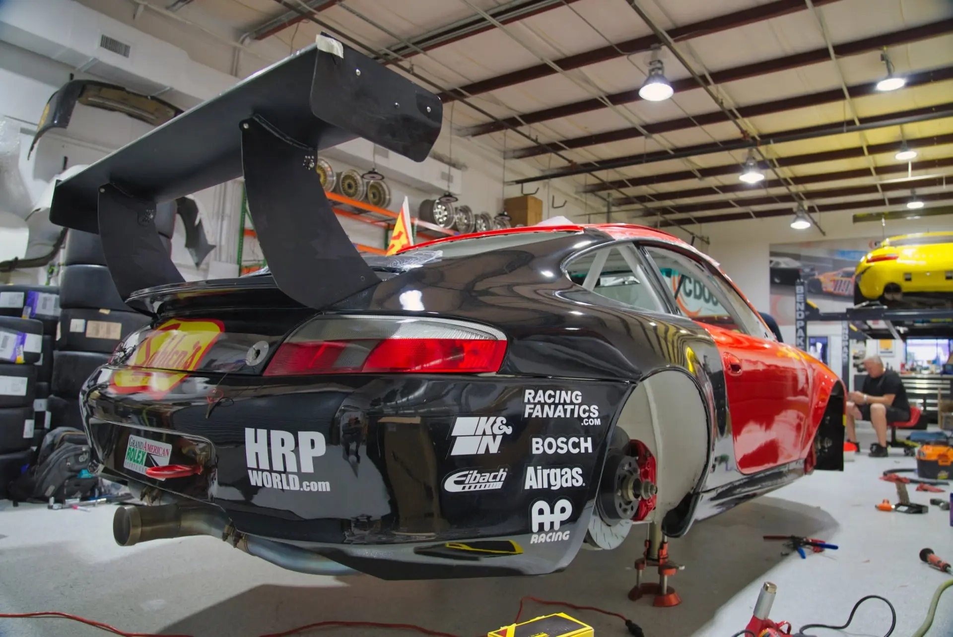 Porsche 911 GT3 Cup race car with rear wing on jack stands inside the DAS Sport shop