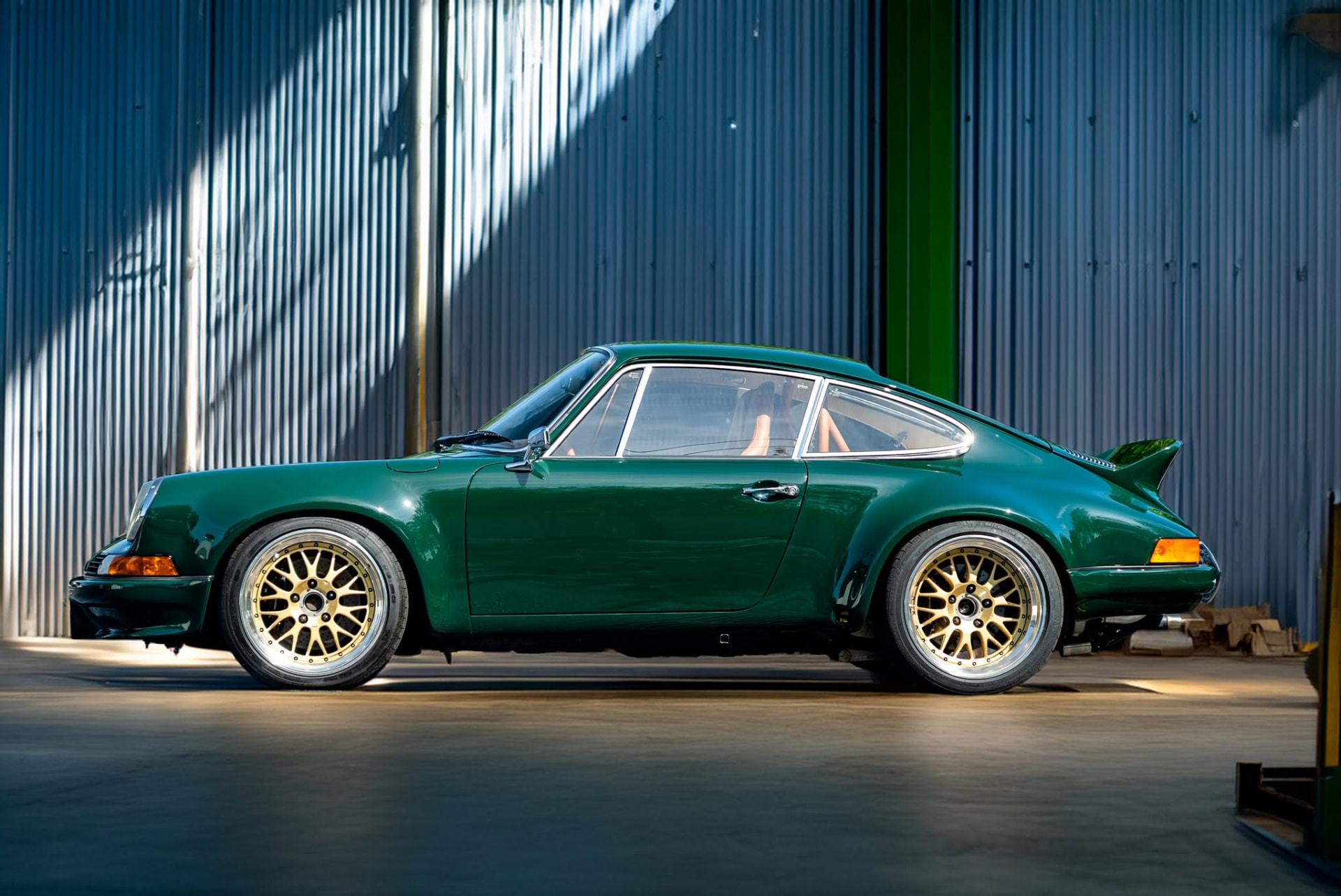 Irish green classic Porsche 911 backdate in profile inside a sunlit workshop